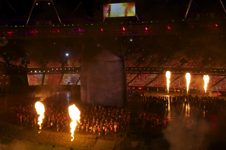 a lot of people with fire torches on a stadium stage