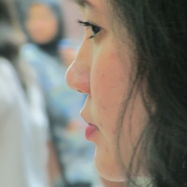 a young woman looks to her right as she holds her cellphone up