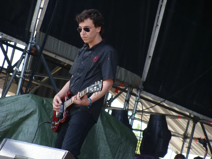 man with glasses playing guitar in front of stage