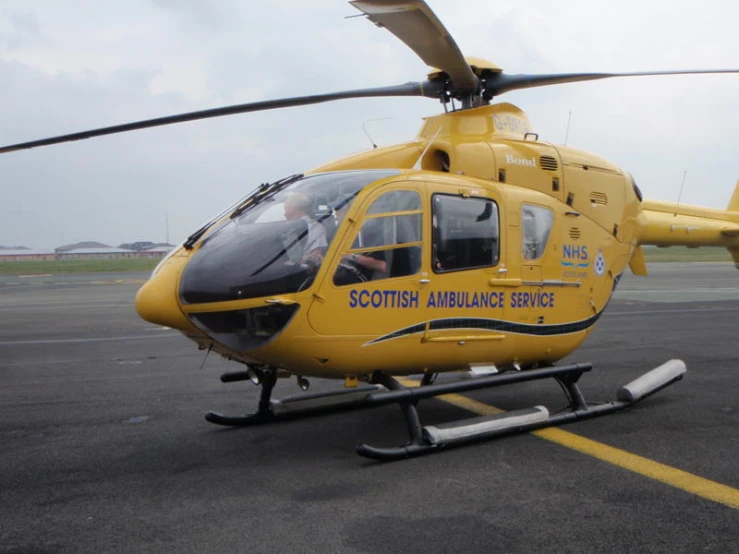 a yellow helicopter sitting on a landing strip