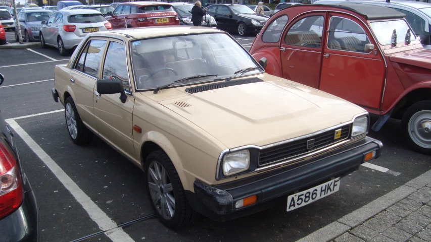 a beige car sits parked in a parking lot near other cars