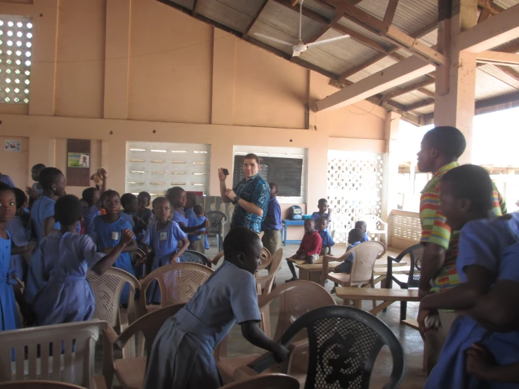 a man stands at the microphone in front of a group of school children