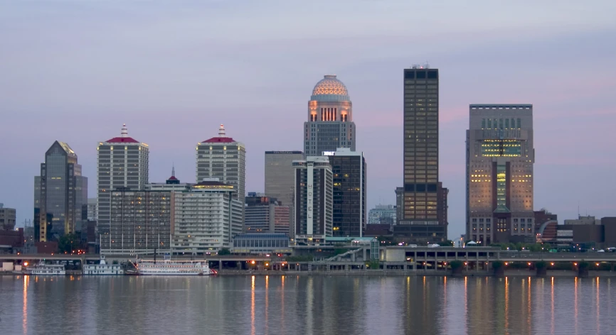 the view of skyscrs at dusk on a lake in a city