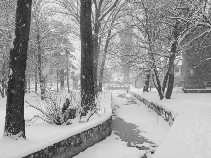 snowy scene of a garden bench and stream in black and white