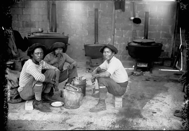 black and white po of three men sitting on the ground