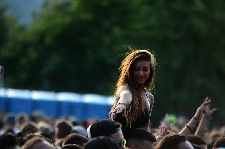 there is a young woman standing in the crowd with arms outstretched