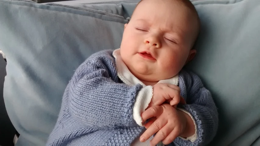 a baby asleep on a couch with it's eyes closed