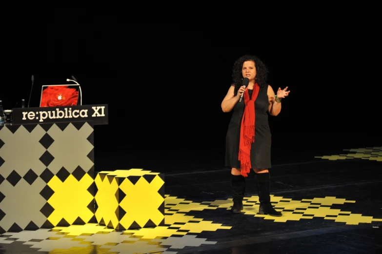 a woman is speaking on stage with a black and white backdrop