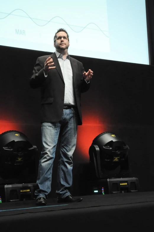 a man standing on stage with his hands in his pockets