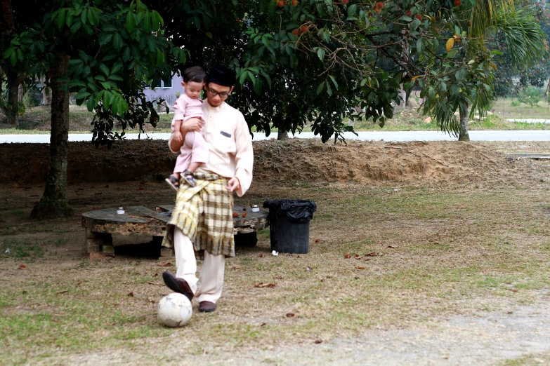 a man and baby standing on top of a grass field