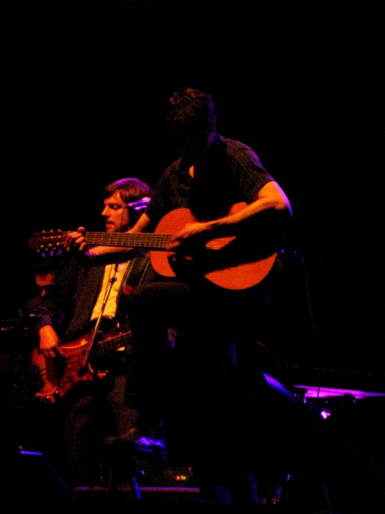 some musicians with guitars in a dark background