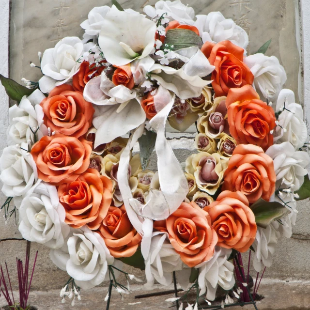 a white and orange bouquet with roses is shown