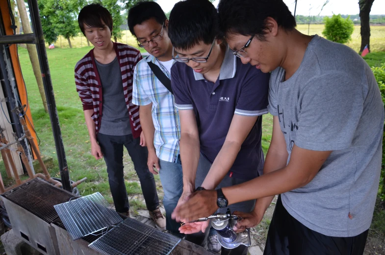 three young men preparing food at a picnic