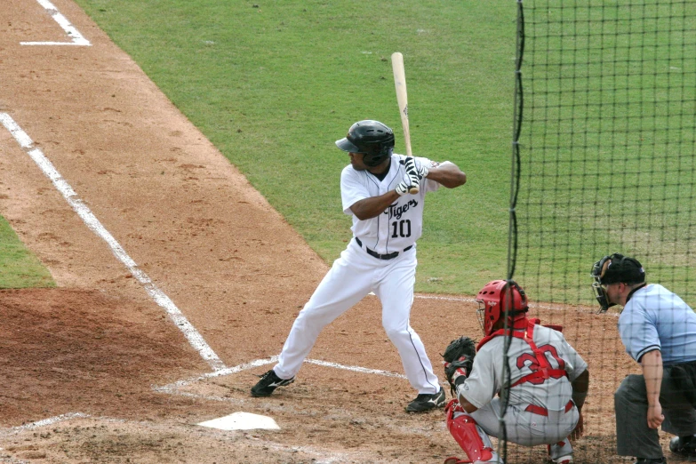 a man in white uniform standing next to home plate with a bat