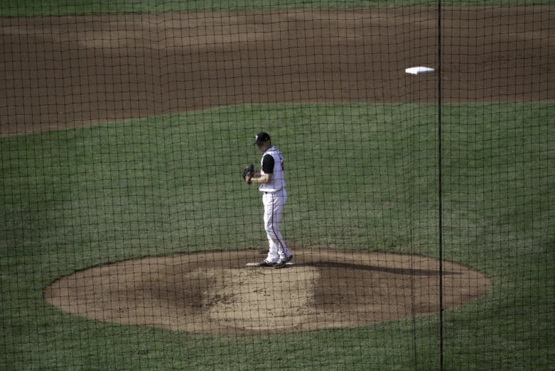 the man in white stands on the pitchers mound