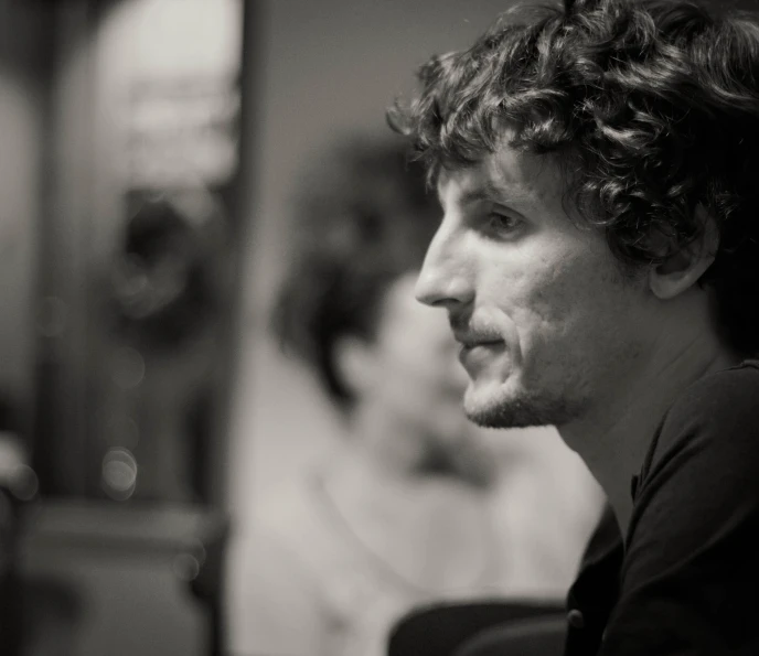 a young man with curly hair looking off to his right