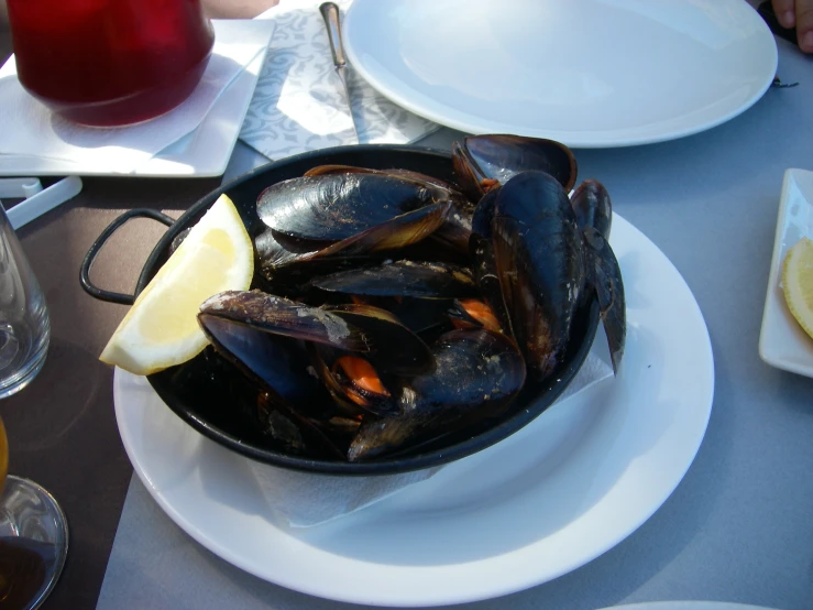 there is a pan with mussels and lemon on it