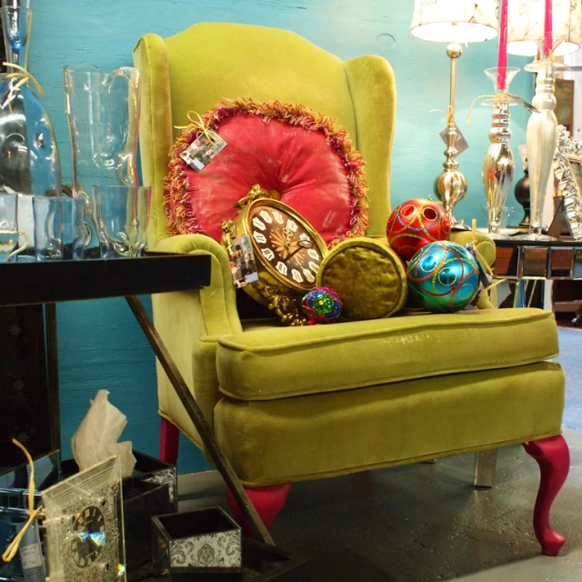 a green chair in front of a table with vases and ornaments