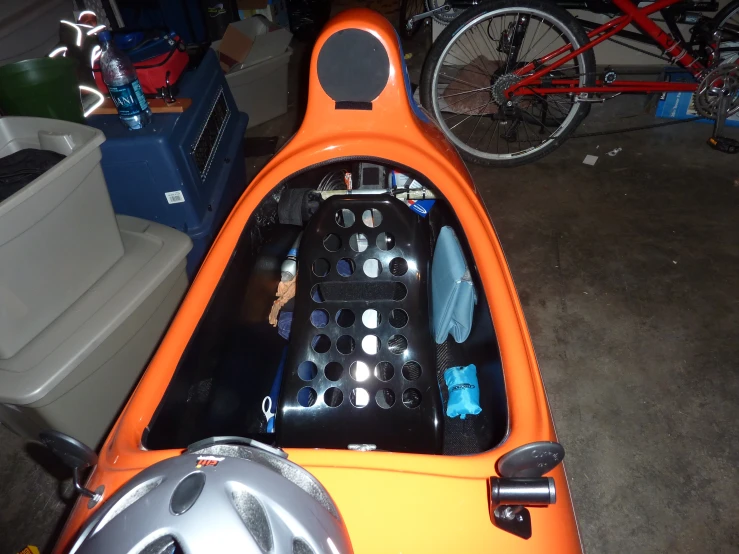 an orange colored kayak and a bicycle in a room