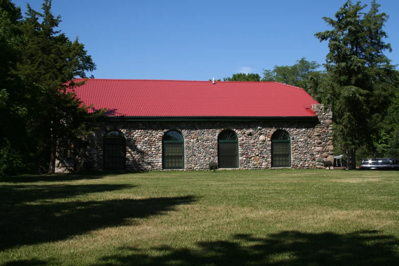 a building with red roof sitting in the middle of a field