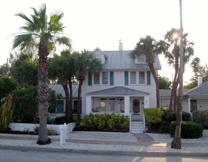 the exterior of a beach house is white with green shutters