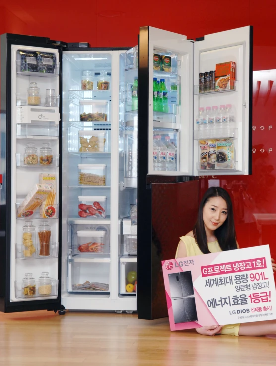 a woman holding a sign in front of an empty refrigerator