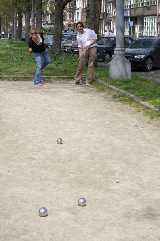 two people playing boccquet in the park, one swinging at an object