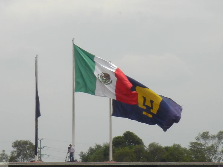 a flag and a mexican flag flying in the wind