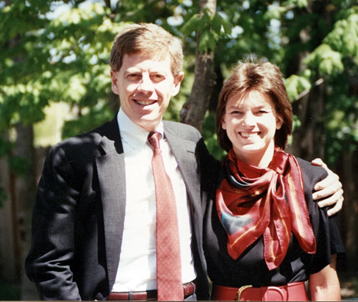 man and woman standing in front of some trees