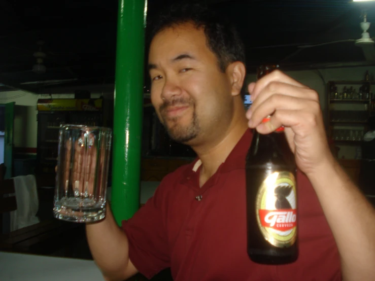 a man holding up a bottle and some glass