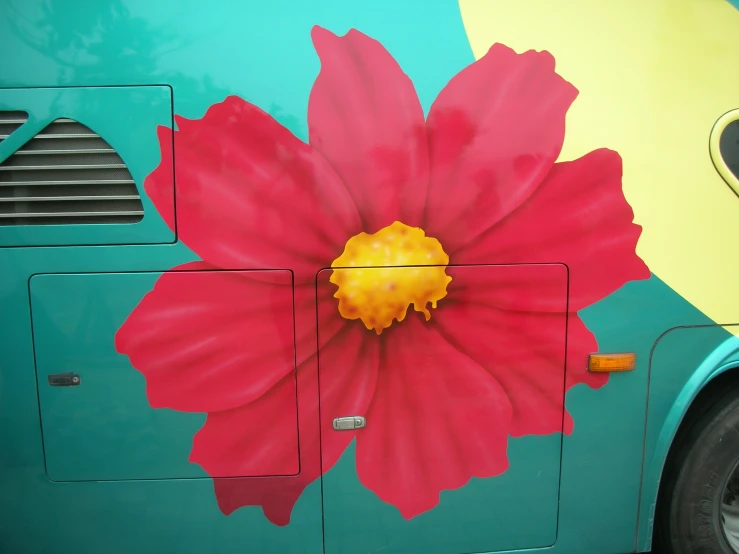 the side of a brightly colored bus decorated with large red flowers