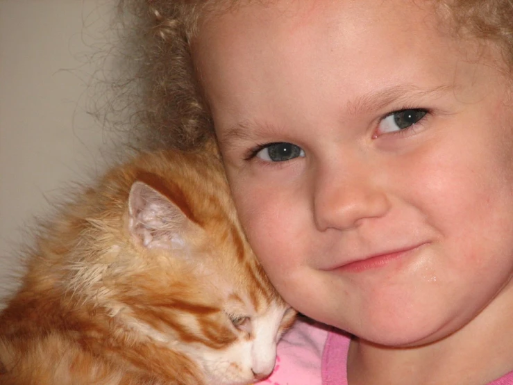 a small child that is hugging a orange cat