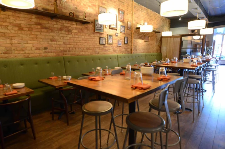 a restaurant with tables and green benches and a bunch of chairs