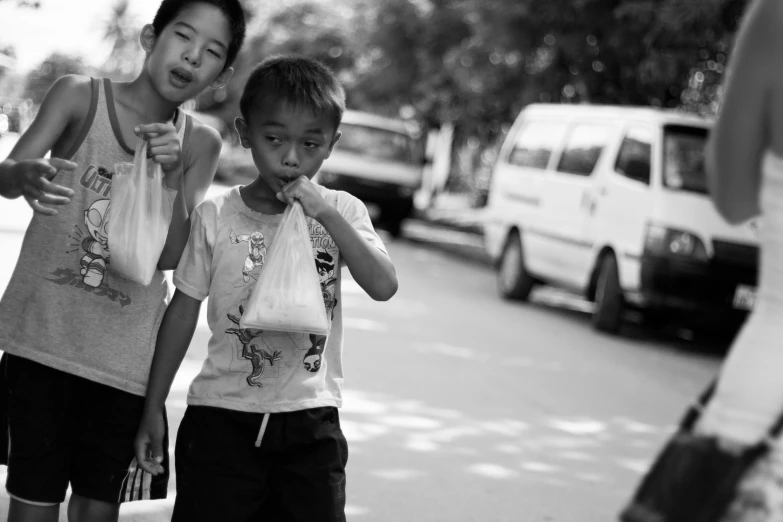 two boys with bags are walking on the street