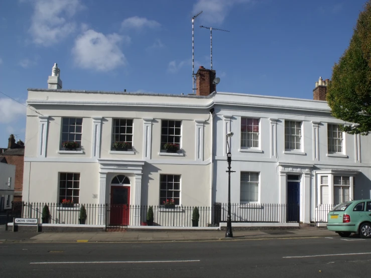 an old white building with several windows in front of a street