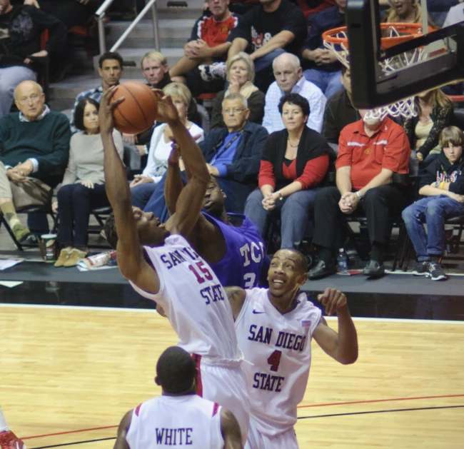 two men play basketball in an arena while people watch