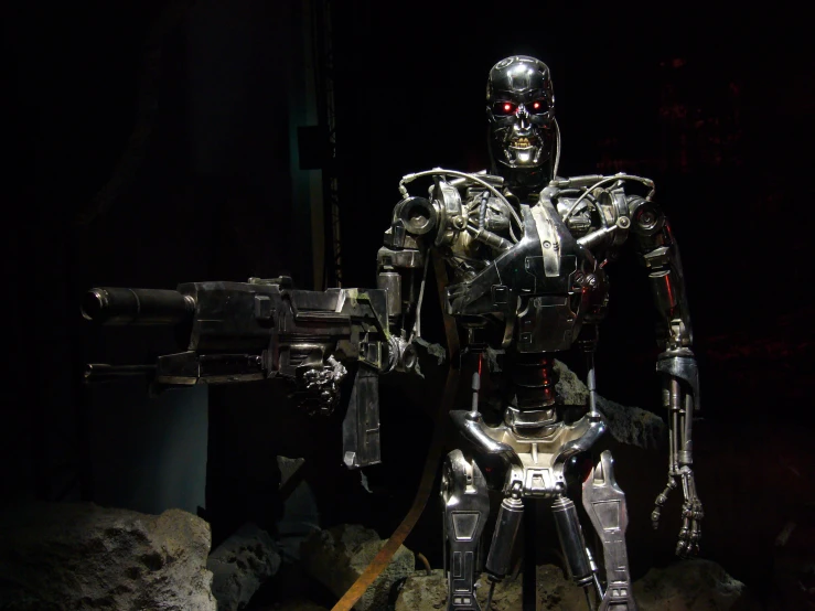 a robot is holding a gun and posing in a darkened room
