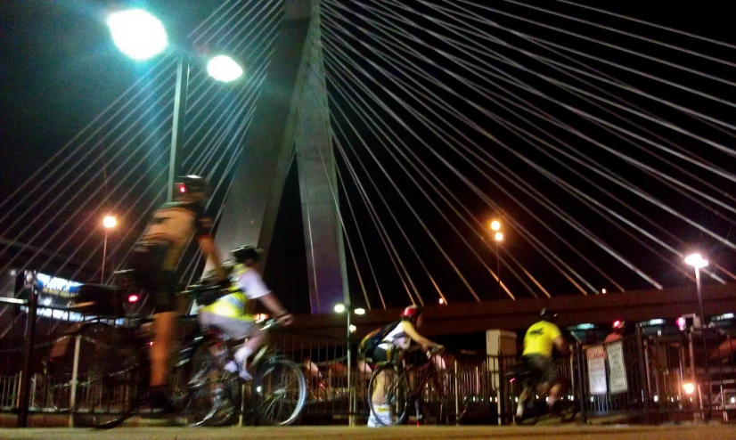 the group of people ride bikes over the bridge