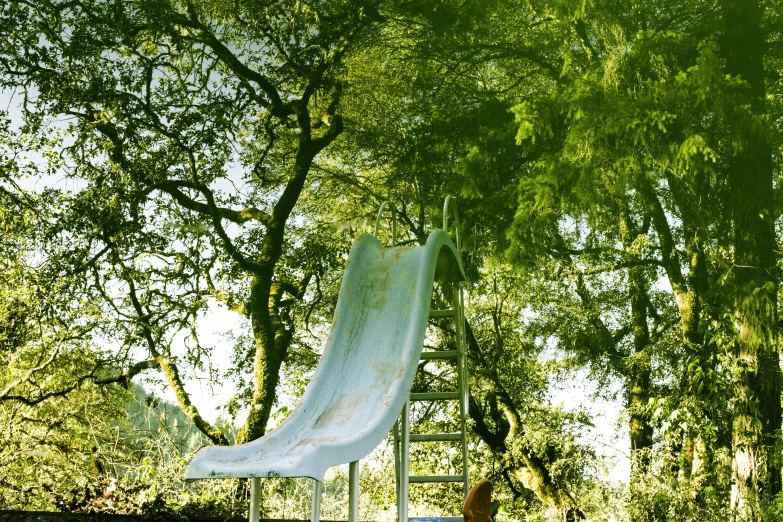 an empty playground next to green trees in the summer