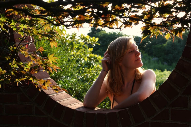 woman in back of window with leaves on nches