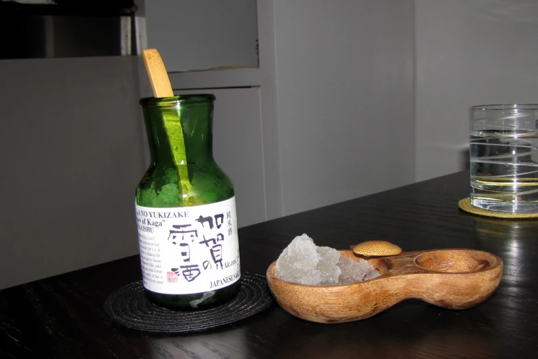 the bottle is beside a spoon and some salt on the table