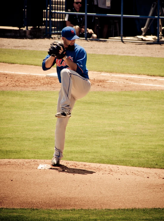 a baseball pitcher is on the mound in mid pitch