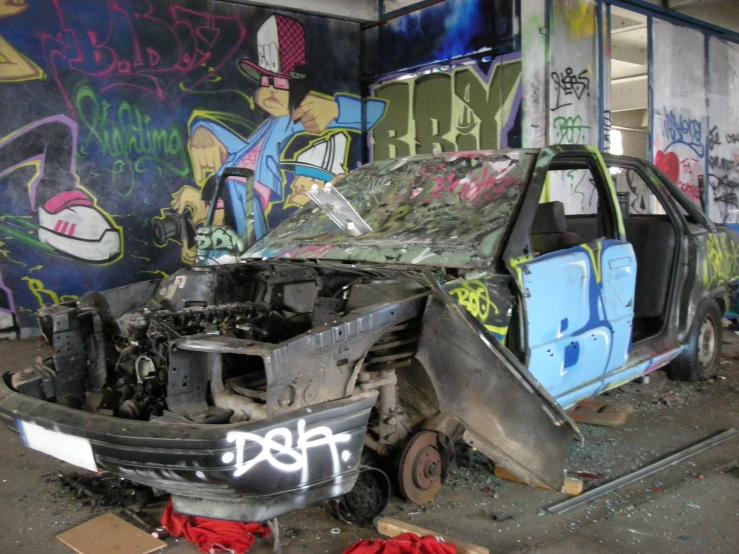 an abandoned car sits in a garage with graffiti on the walls