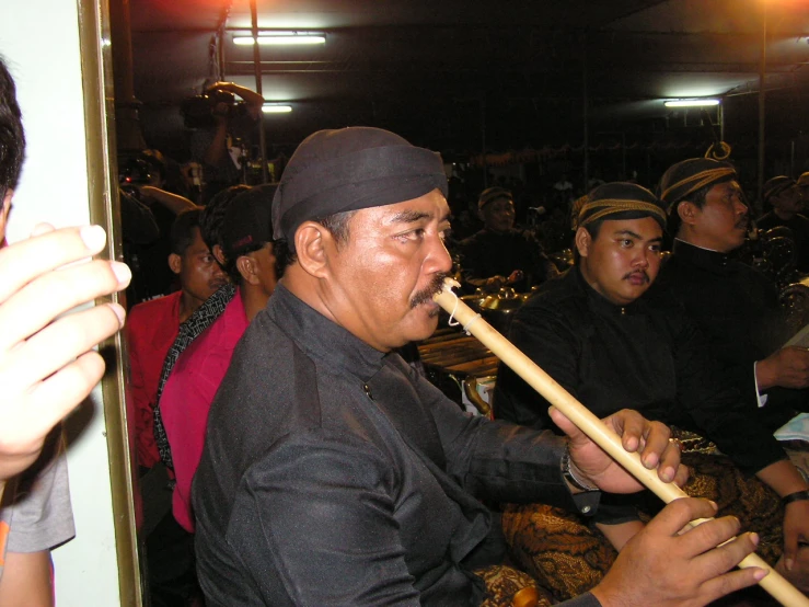 man in turban and hat playing the flute