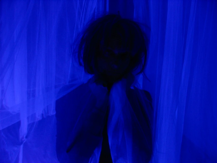 a dark - haired woman is covering her face with a blue curtain