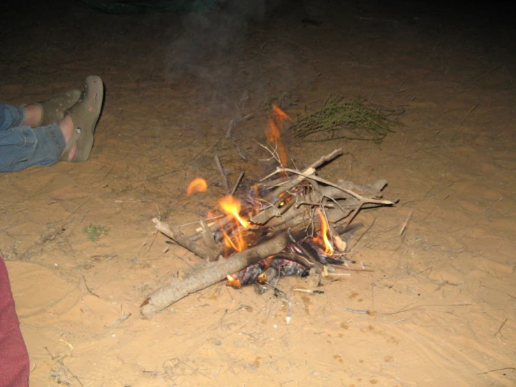 a small campfire is seen in the middle of a barren area