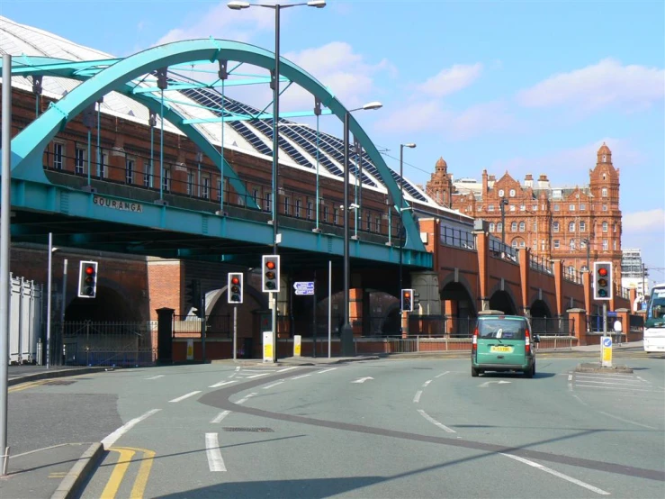 green bus stopped under a metal blue bridge