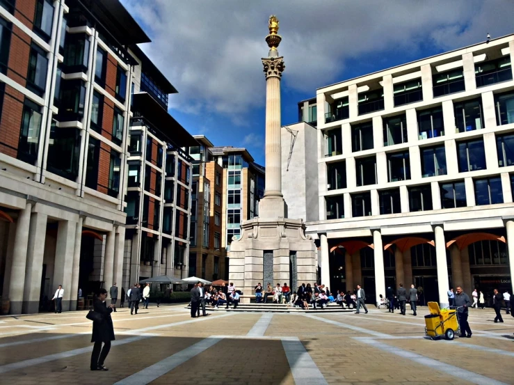 several buildings with pillars surrounding and a tall stone column at the center