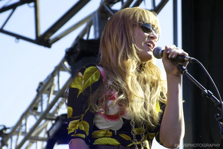 a woman holding a microphone in front of a stage