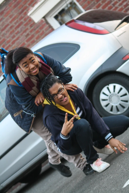 the two girls are posing for a picture outside of a car